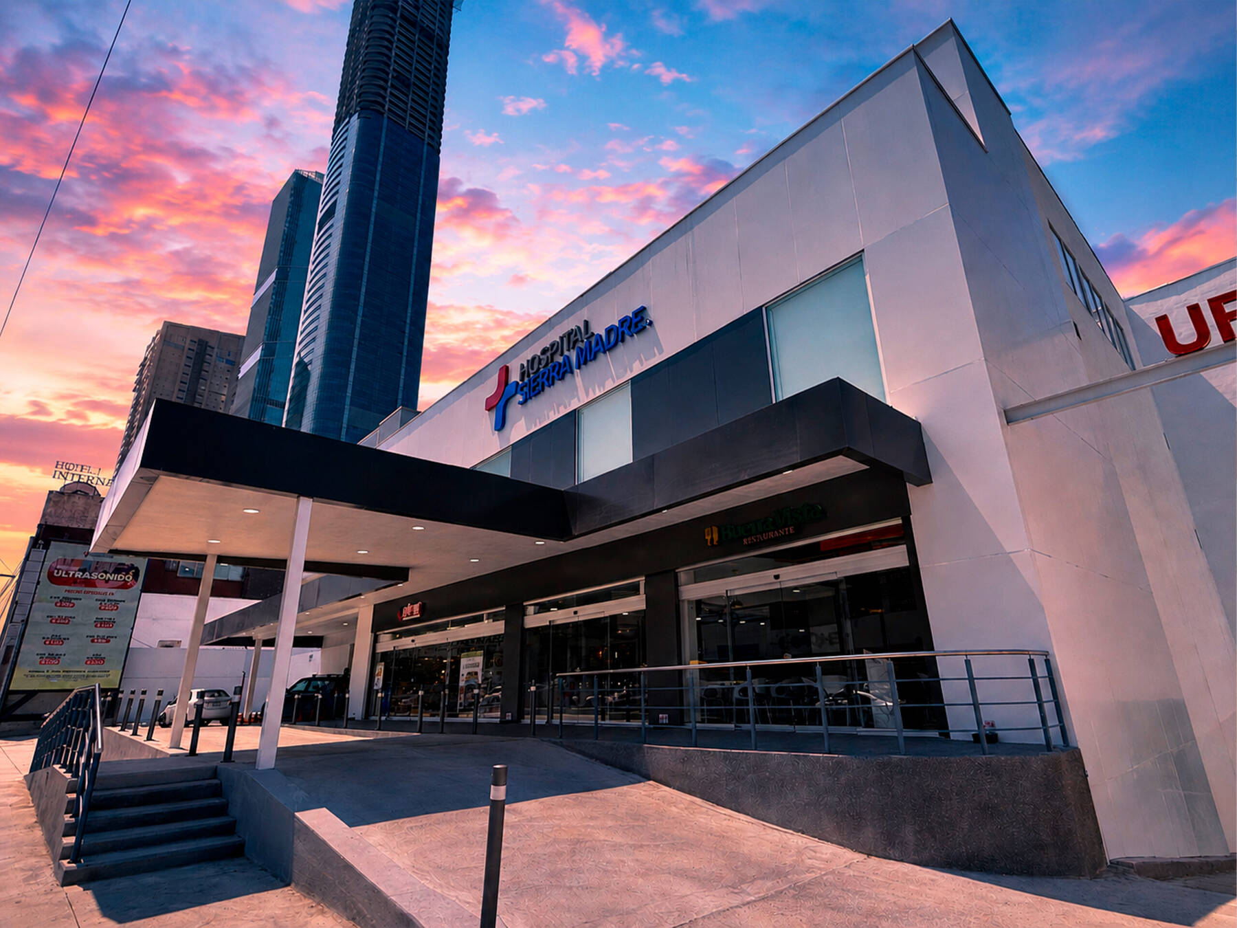 Entrada del Hospital Sierra Madre al atardecer, con el logo en la fachada blanca